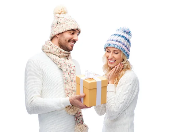 Smiling couple in winter clothes with gift box — Stock Photo, Image