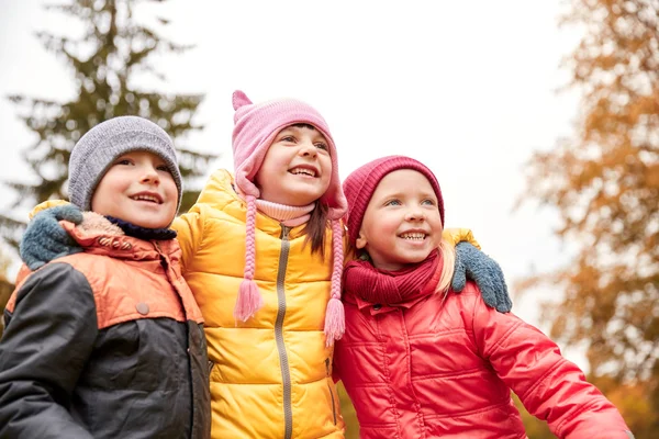 Gruppo di bambini felici che si abbracciano nel parco autunnale — Foto Stock