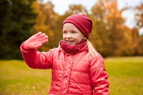 Menina feliz acenando mão no parque de outono — Fotografia de Stock