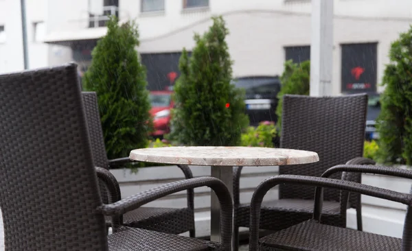 Table and chairs on street cafe terrace under rain — Stock Photo, Image