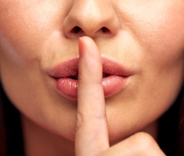 close up of young woman holding finger on lips clipart