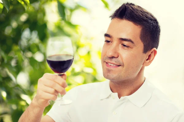 Homem feliz bebendo vinho tinto de vidro — Fotografia de Stock