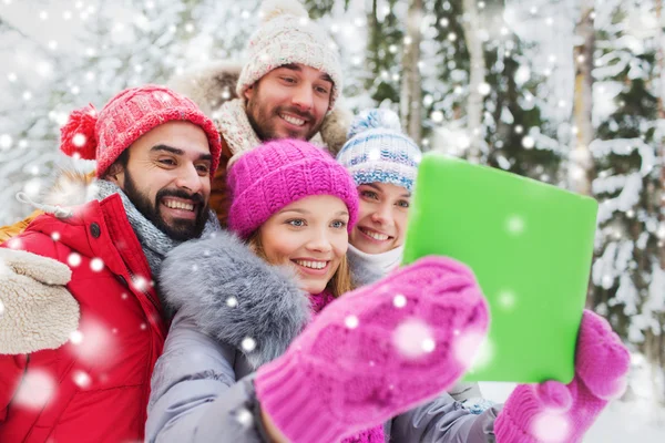 Lachende vrienden met tablet pc in winter forest — Stockfoto