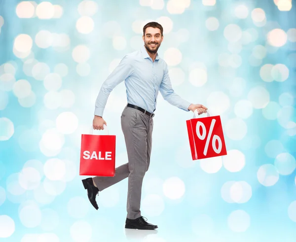 Smiling man walking with red shopping bag — Stock Fotó