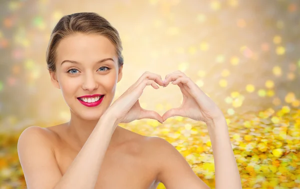 Smiling young woman showing heart shape hand sign — Stock Photo, Image