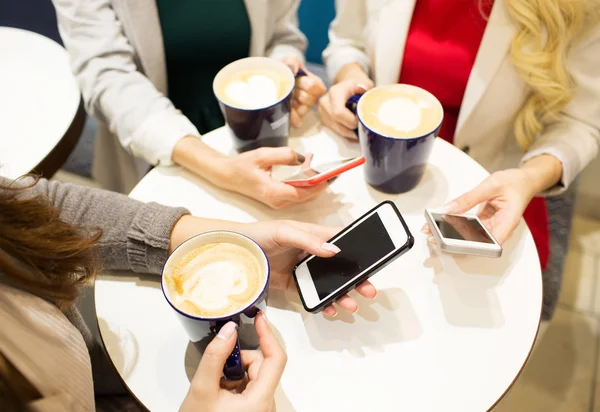 close up of hands with coffee cups and smartphones