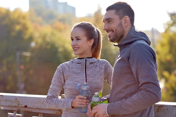 Pareja sonriente con botellas de agua al aire libre —  Fotos de Stock