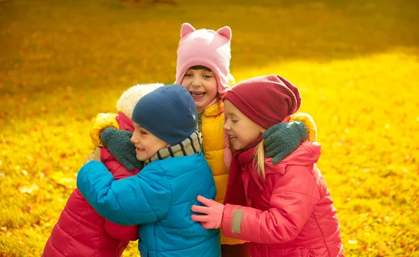 Grupo de crianças felizes abraçando no parque de outono — Fotografia de Stock