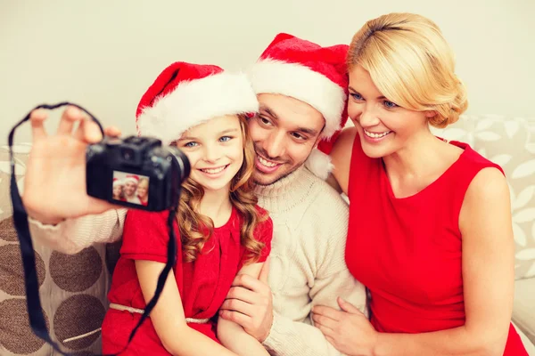 Lächelnde Familie mit Weihnachtsmann-Helfermützen beim Fotografieren — Stockfoto