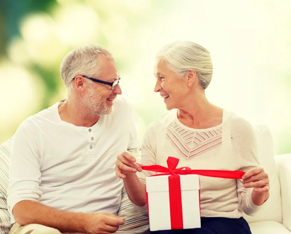 Feliz pareja de ancianos con caja de regalo en casa —  Fotos de Stock