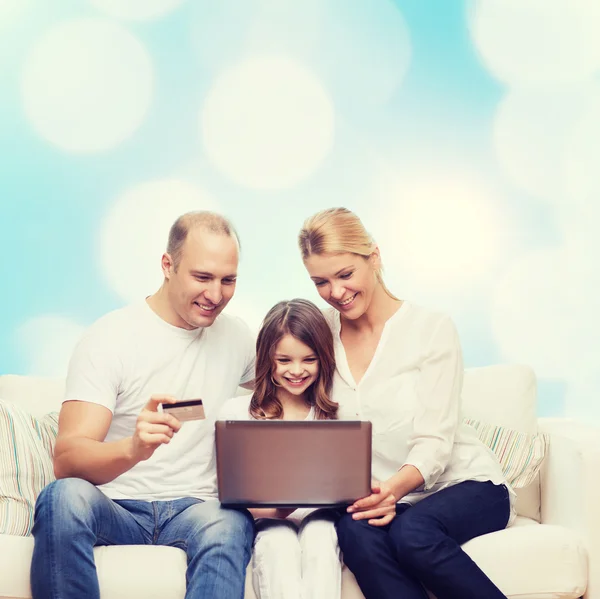 Familia feliz con ordenador portátil y tarjeta de crédito —  Fotos de Stock