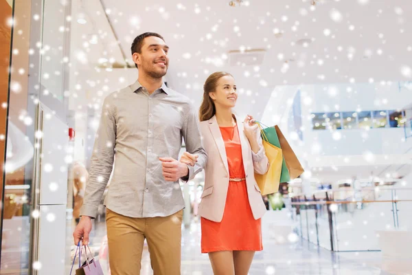 Feliz jovem casal com sacos de compras no shopping — Fotografia de Stock