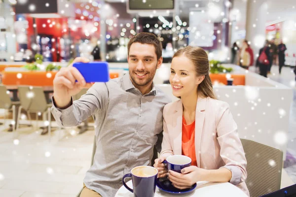 Счастливая пара со смартфоном, делающая селфи в торговом центре — стоковое фото