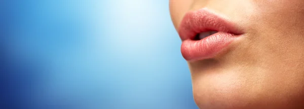 Primer plano de labios de mujer joven sobre azul — Foto de Stock