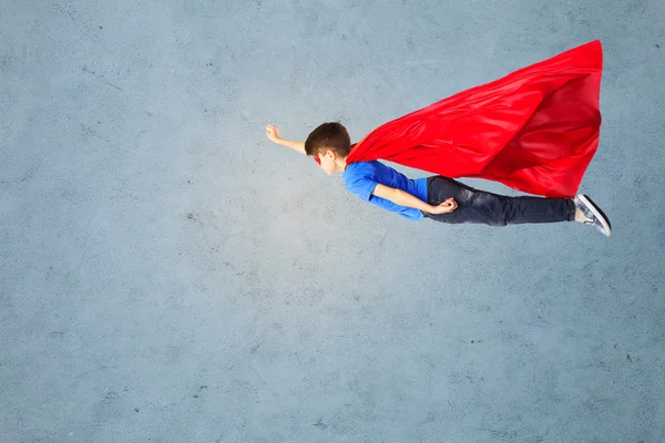 Niño en capa de superhéroe rojo y máscara volando en el aire —  Fotos de Stock