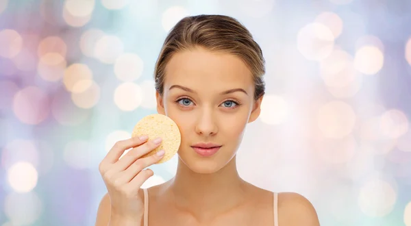 Mujer joven limpiando la cara con esponja exfoliante — Foto de Stock