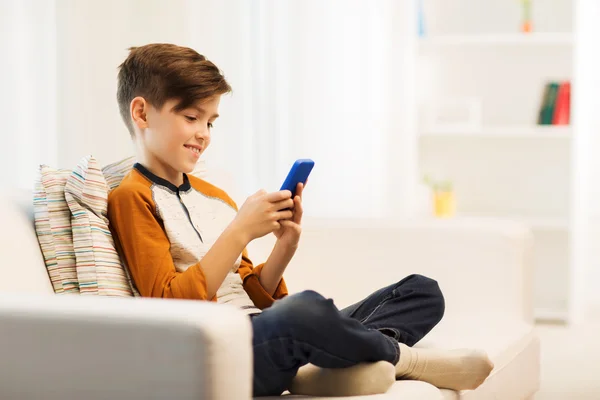 Chłopiec ze smartfonem smsowanie lub zabawy w domu — Zdjęcie stockowe