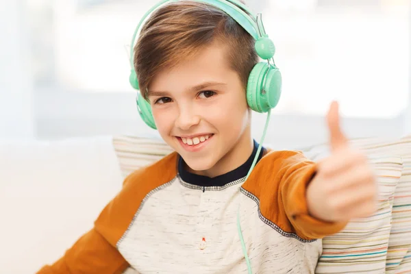 Happy boy in headphones showing thumbs up at home — Stock Photo, Image