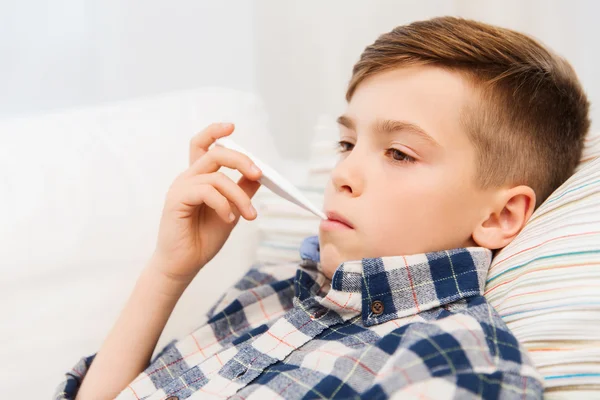 Chory chłopiec z grypa i termometr w domu — Zdjęcie stockowe