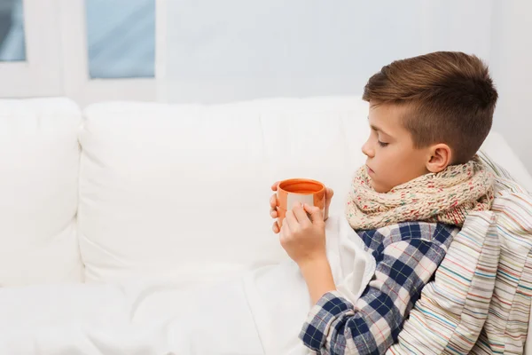 Malade garçon avec grippe dans écharpe boire du thé à la maison — Photo