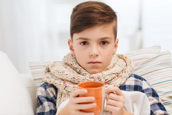 Grippekranker Junge im Schal trinkt zu Hause Tee — Stockfoto