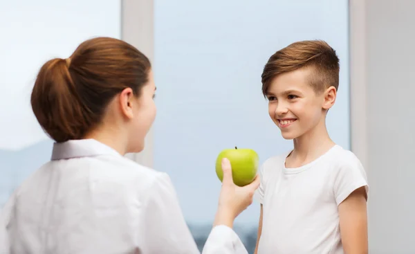 Врач с зеленым яблоком и счастливый мальчик в клинике — стоковое фото