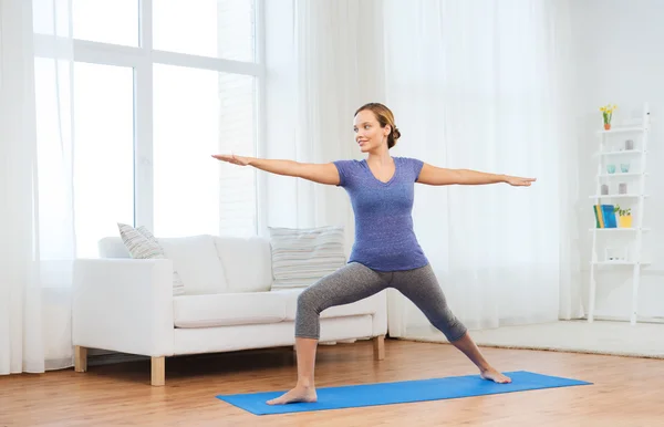 Mujer haciendo yoga guerrero pose en mat — Foto de Stock