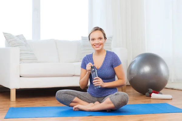 Mujer feliz con botella de agua haciendo ejercicio en casa — Foto de Stock