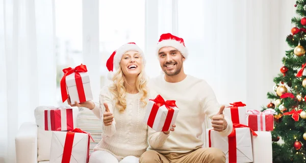 Casal feliz com presentes de Natal e polegares para cima — Fotografia de Stock