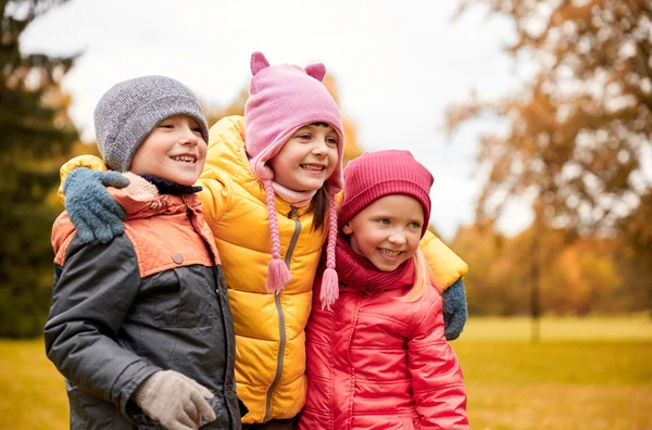 Gruppo di bambini felici che si abbracciano nel parco autunnale — Foto Stock