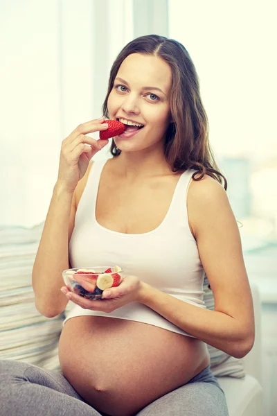 Happy pregnant woman eating fruits at home — Stock Photo, Image