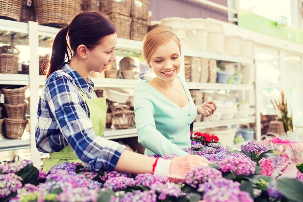 Glada kvinnor välja blommor i växthus — Stockfoto