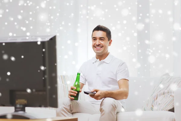 笑みを浮かべて男テレビを見て、家でビールを飲む — ストック写真