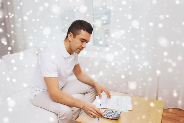 Hombre con papeles y calculadora en casa — Foto de Stock