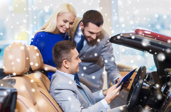 Couple heureux avec concessionnaire de voitures en salon ou salon de l'auto — Photo