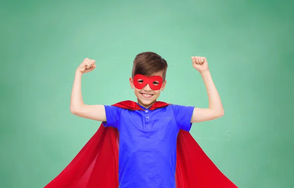 Boy v červené super hrdina mys a maska zobrazující pěsti — Stock fotografie