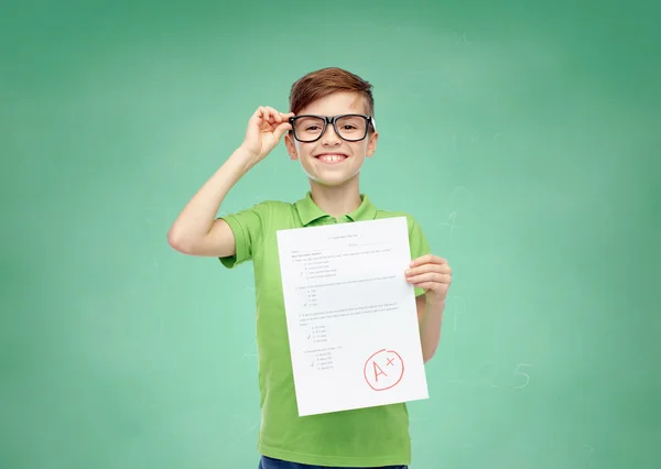 Happy boy in eyeglasses holding school test result — Stockfoto