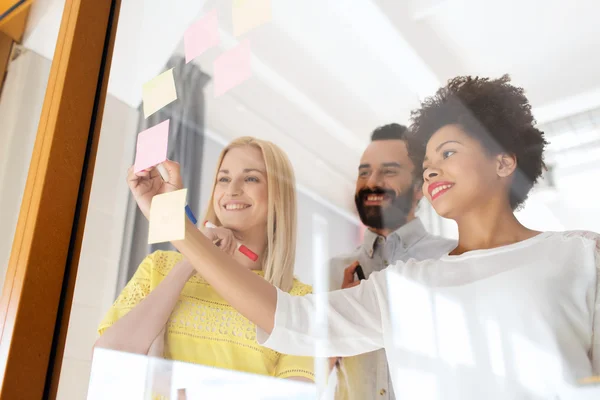 Feliz equipo creativo escribiendo en pegatinas en la oficina —  Fotos de Stock