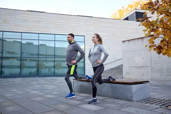 Happy man and woman exercising on bench outdoors — Stock Photo, Image