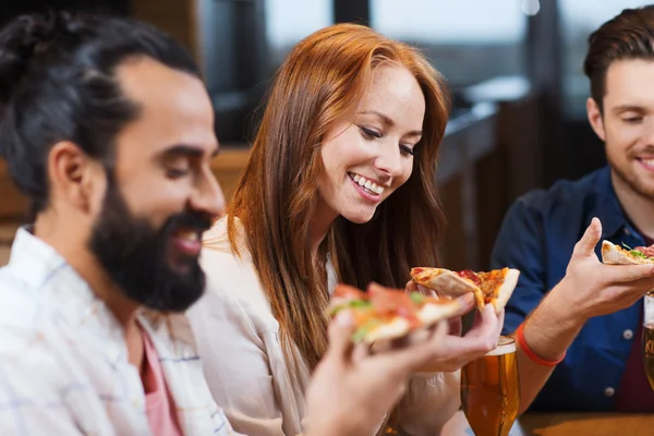 Друзья едят пиццу с пивом в ресторане — стоковое фото