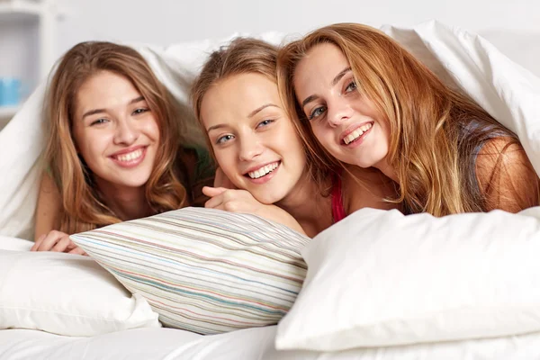 Happy young women in bed at home pajama party — Stock Photo, Image