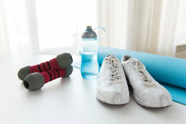 Primer plano de la botella, mancuernas, zapatillas de deporte y alfombra — Foto de Stock