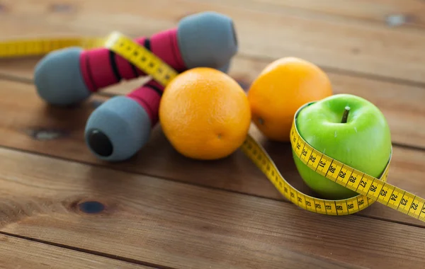 Primer plano de la mancuerna, frutas y cinta métrica — Foto de Stock