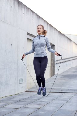woman exercising with jump-rope outdoors clipart