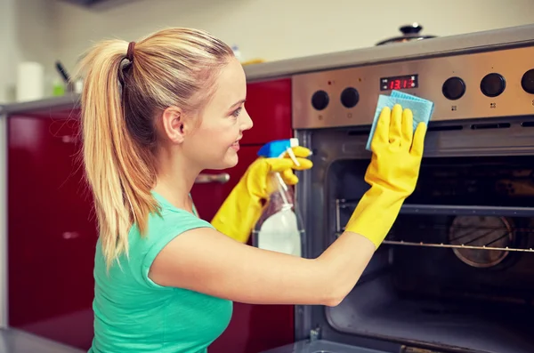 Szczęśliwa kobieta sprzątanie kuchenka w domu kuchnia — Zdjęcie stockowe