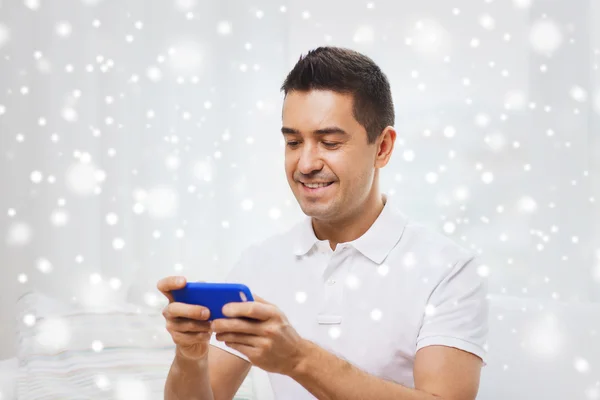 Счастливый человек со смартфоном дома — стоковое фото