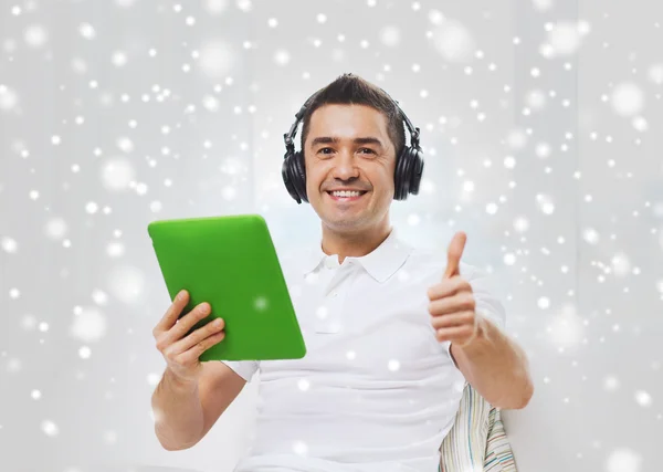 Uomo sorridente con tablet pc e cuffie a casa — Foto Stock