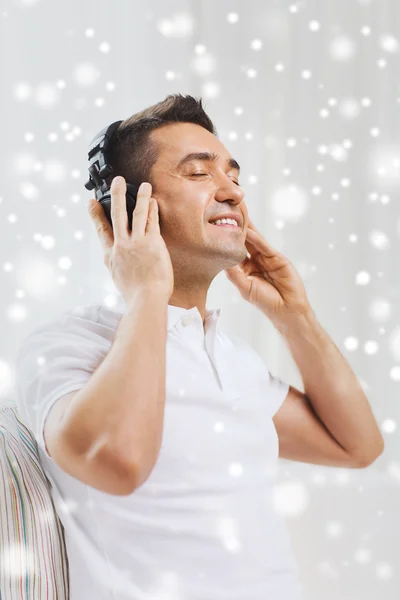 Hombre feliz en auriculares escuchando música en casa —  Fotos de Stock