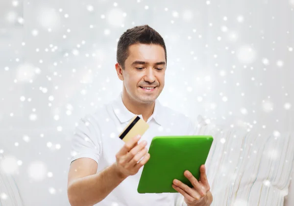 Hombre sonriente que trabaja con la tableta PC y tarjeta de crédito —  Fotos de Stock