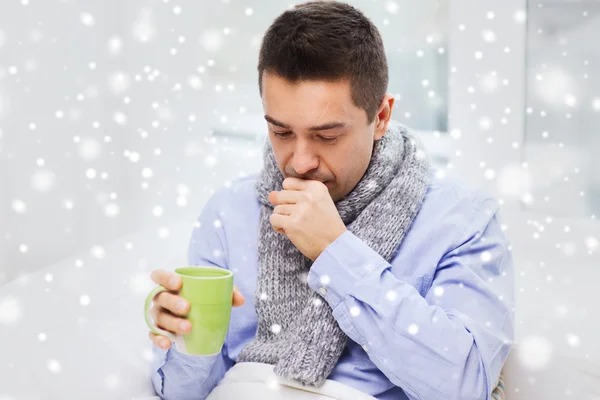 Zieke man met griep drinken thee en hoesten thuis — Stockfoto